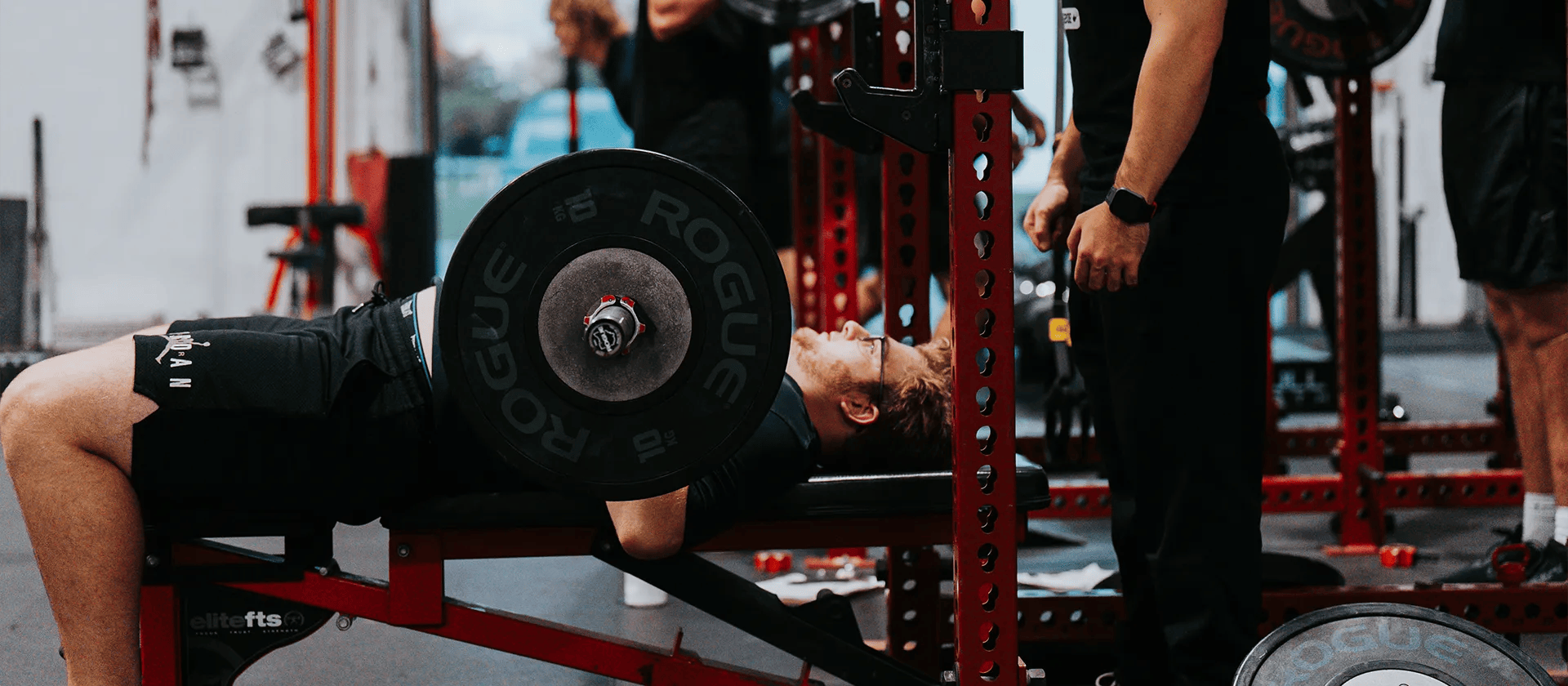 man benching heavy weight at Iron Performance Center